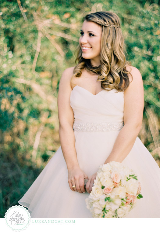 Profile of Aggie bride in wedding gown with beaded belt, white and pink bouquet.